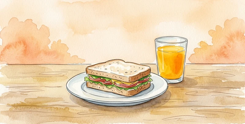 Medio bocadillo en un plato y un vaso de zumo de naranja, sobre una mesa de madera.